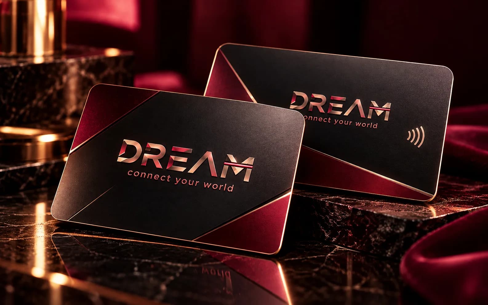 Two black and burgundy Dream cards with gold edges on dark marble